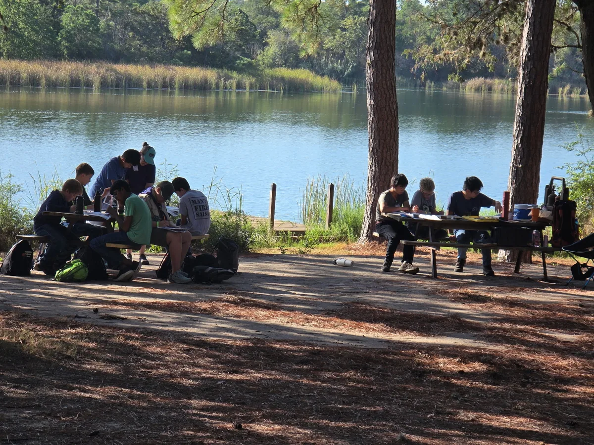 Scouts working at lakeside picnic tables during the STEM camp
