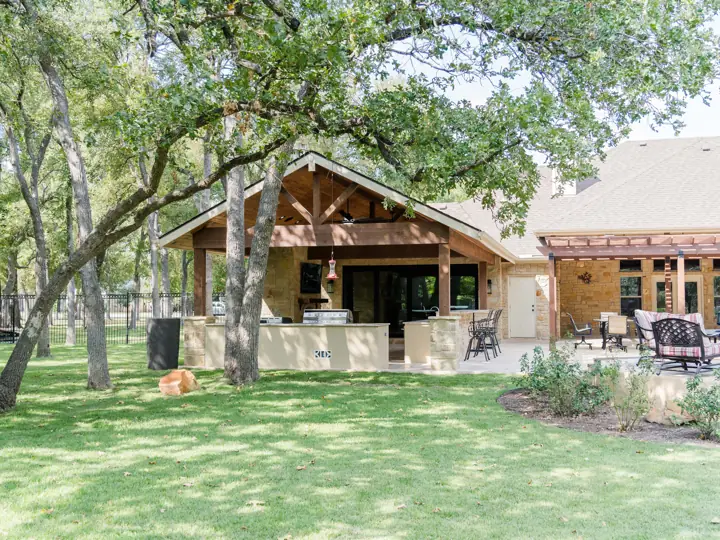 Backyard view of a cedar outdoor kitchen pavilion and pergola