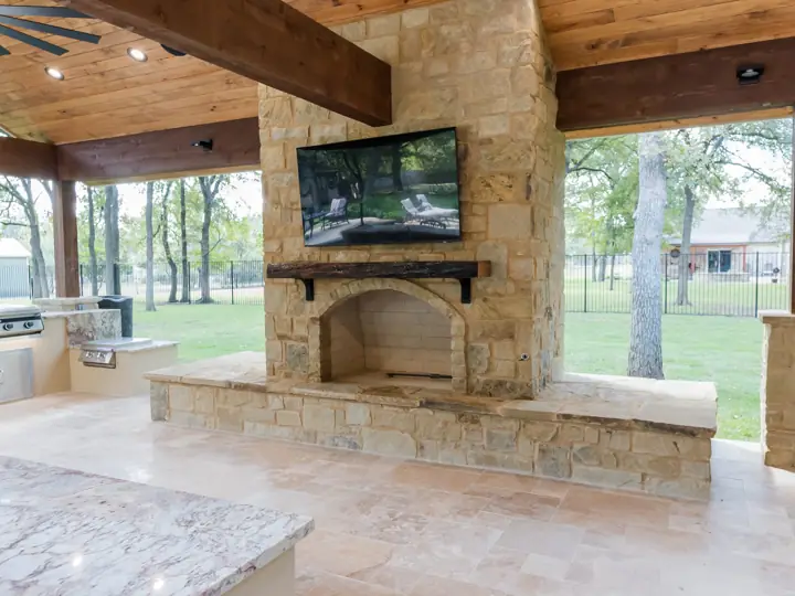 Wood-burning outdoor fireplace with live-edge mantel and mounted TV