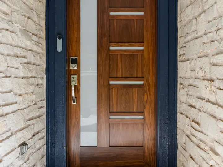 Custom walnut front door with glass inserts on a stone entry