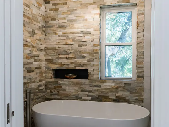 Bathroom remodel with stacked-stone accent wall and freestanding tub