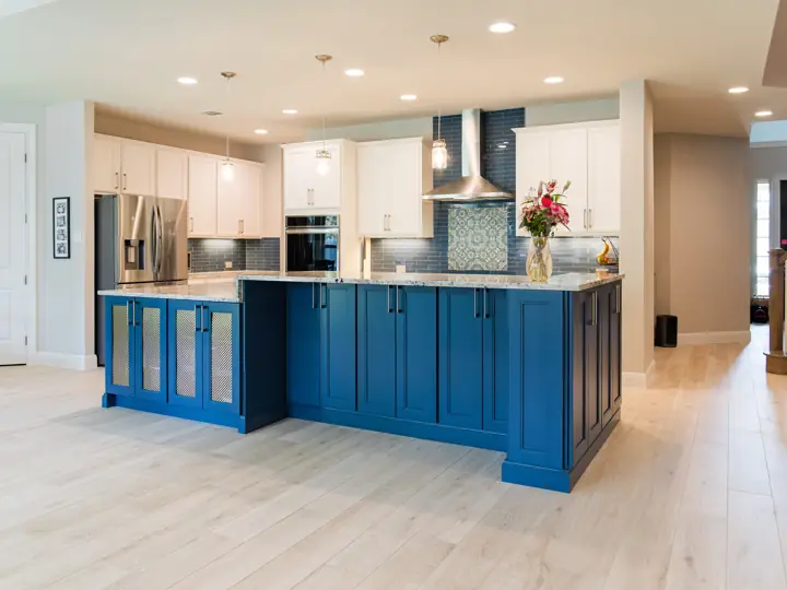 Kitchen remodel with navy blue island, white perimeter cabinets, and wood-look tile floors in Austin, TX