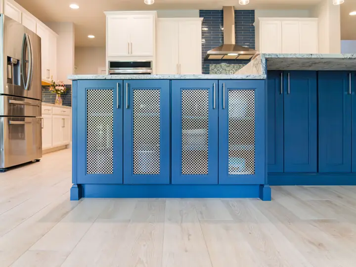 Navy island cabinetry with brass mesh door inserts