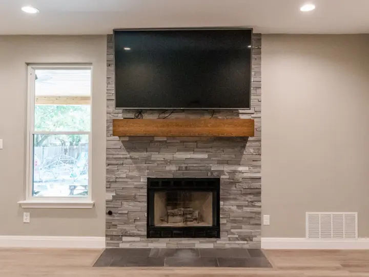 Living room fireplace with stacked stone surround and custom mantle