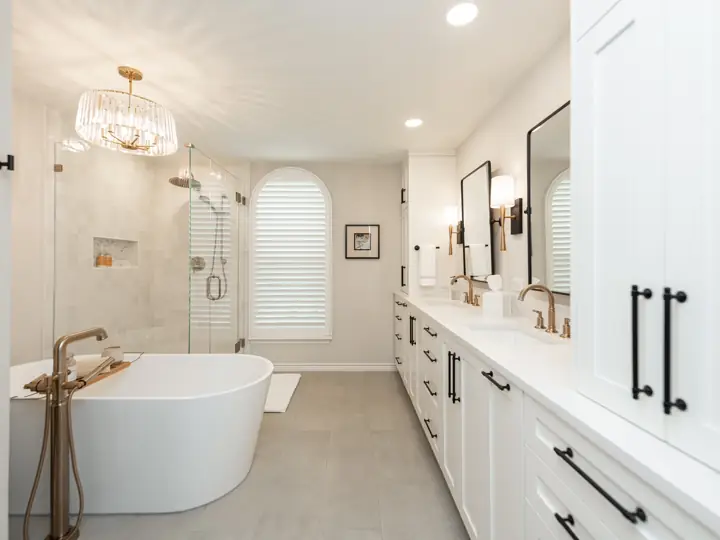 White primary bathroom remodel with brass fixtures and freestanding tub
