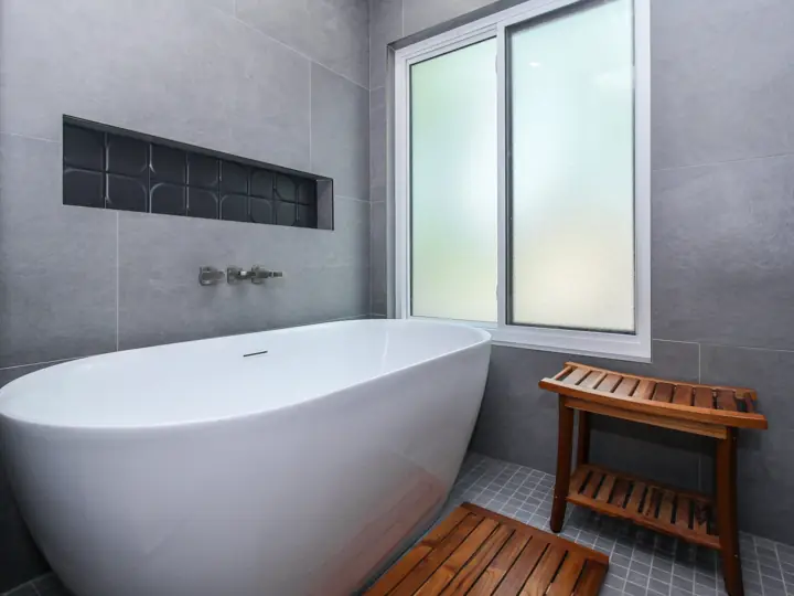 Primary bathroom remodel with freestanding soaking tub and large-format gray tile