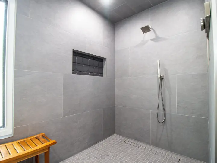 Walk-in shower with large-format tile, niche, and teak bench