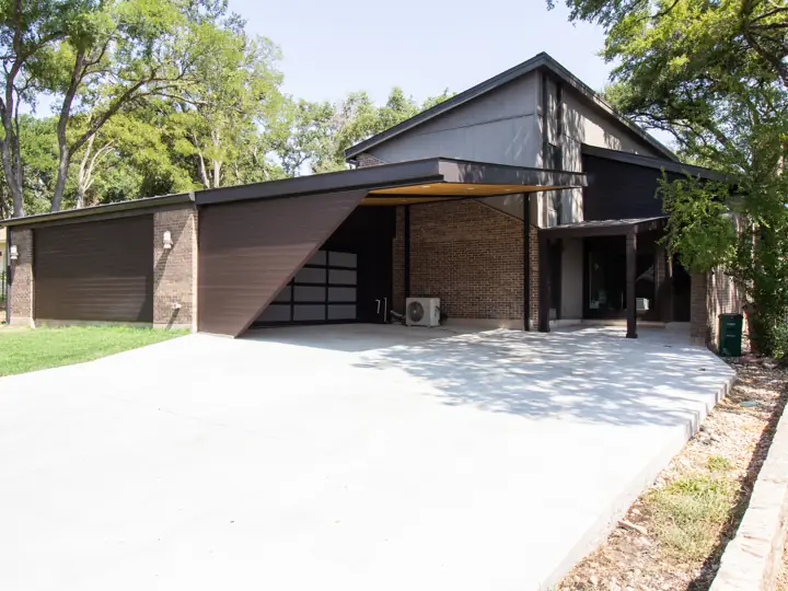 Modern exterior remodel with cantilevered carport and dark siding in Austin, TX