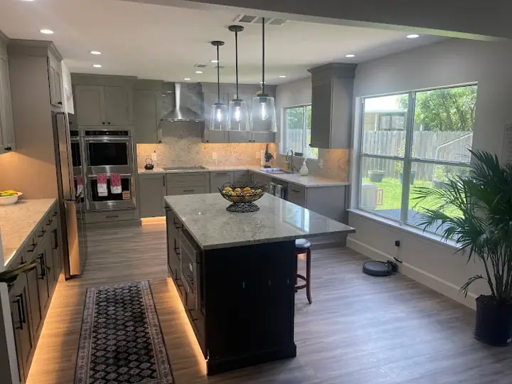 Gray kitchen remodel with dark island, granite counters, and under-cabinet lighting